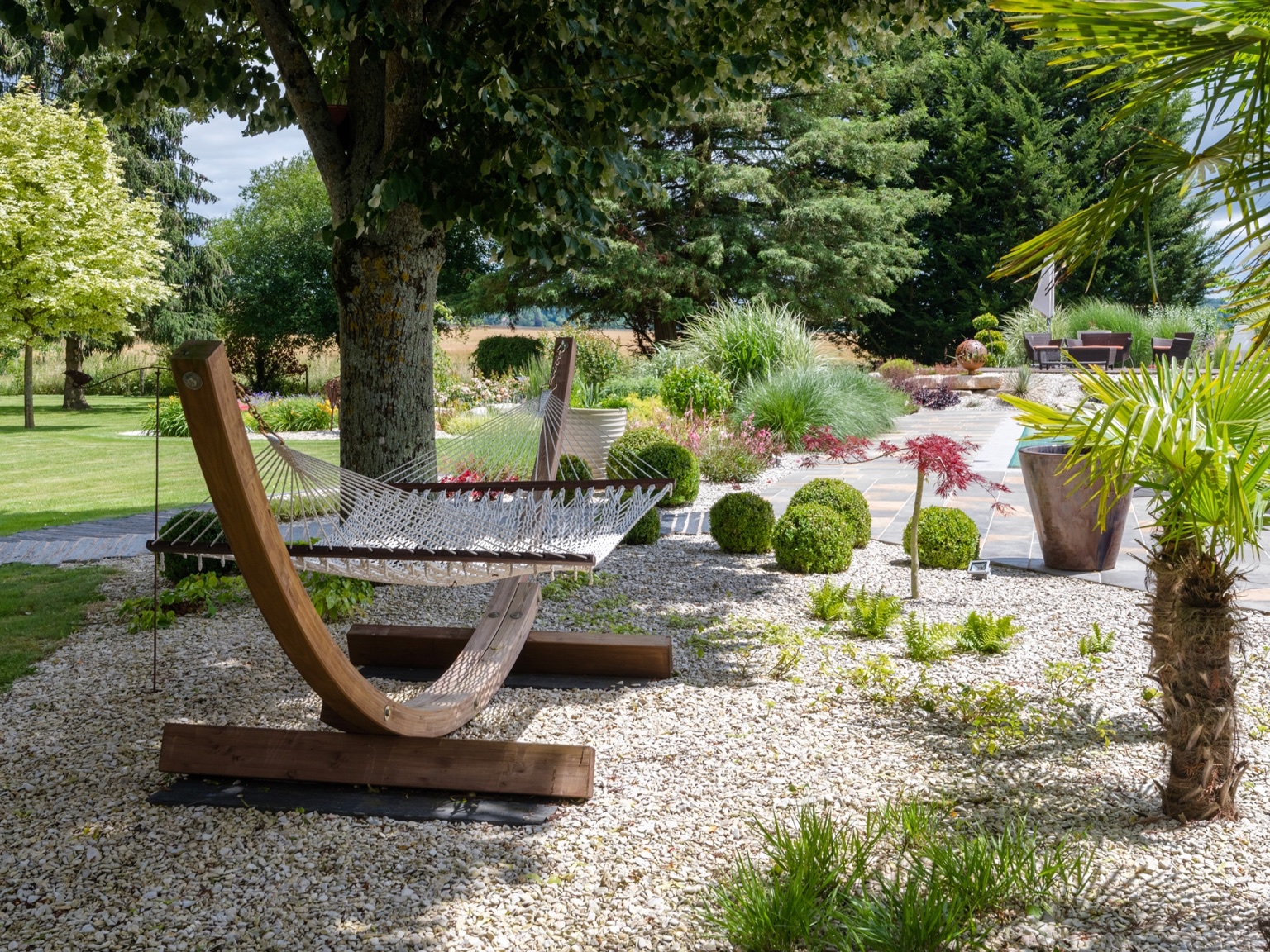 Aménagement paysager avec terrasse, massif et jardin arboré